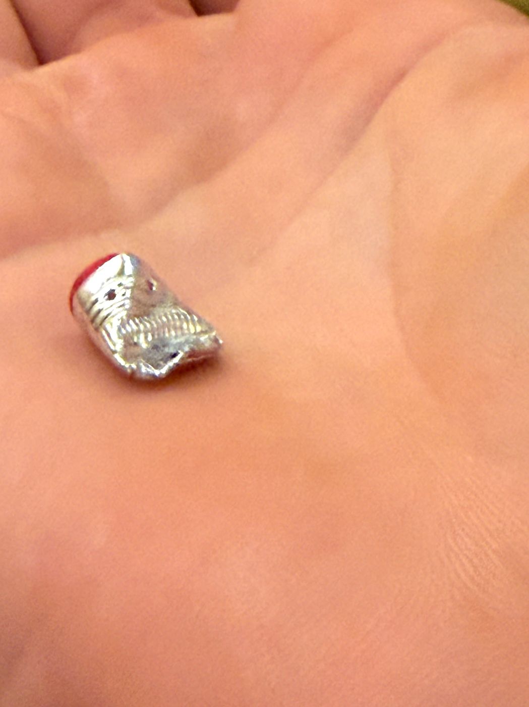 A tiny figure folded out of foil, held in the palm of a hand