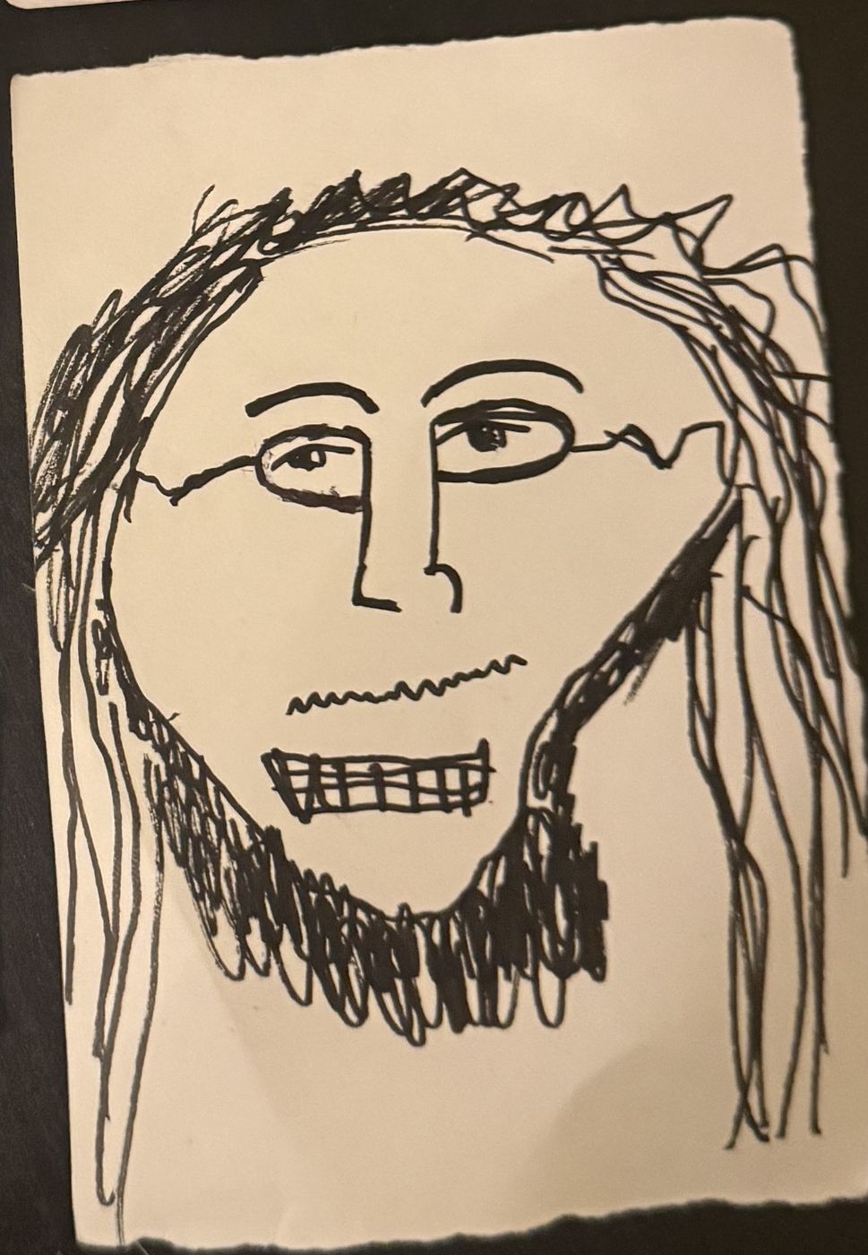 An ink portrait of Max Cohen, long hair and a wide grin, drawn by a participant